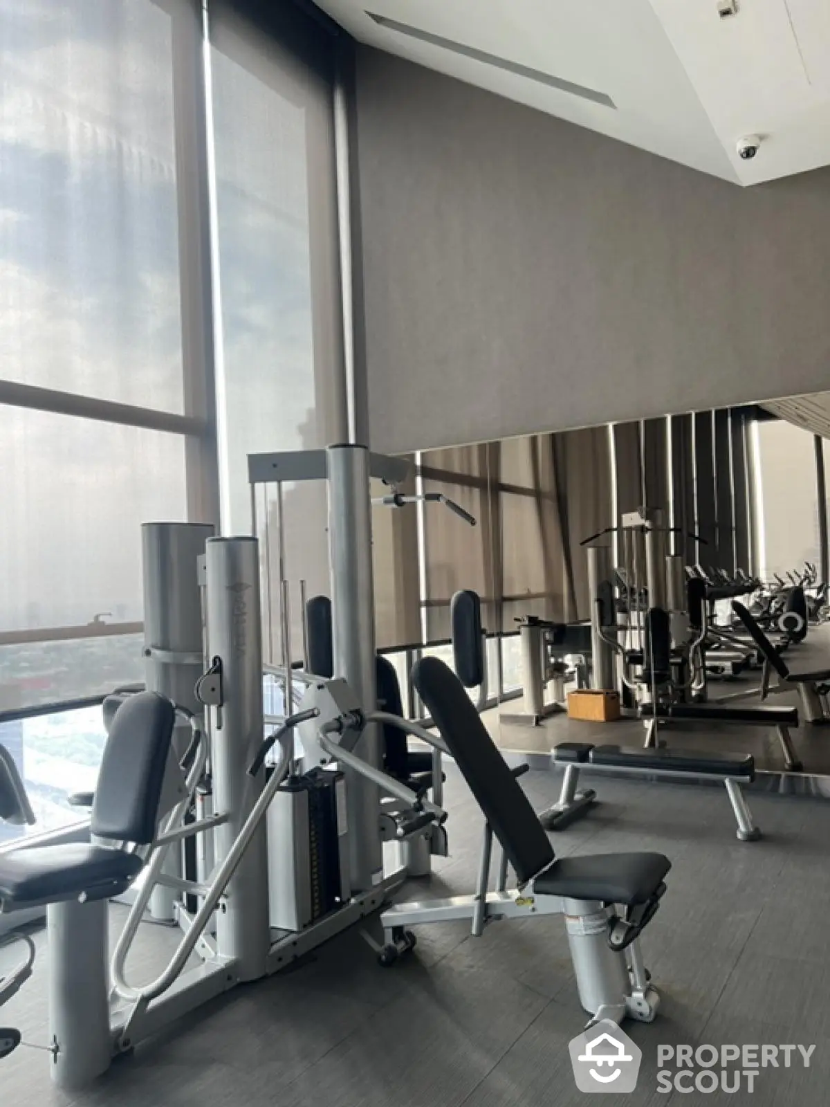 Modern gym with state-of-the-art equipment and floor-to-ceiling windows offering city views.