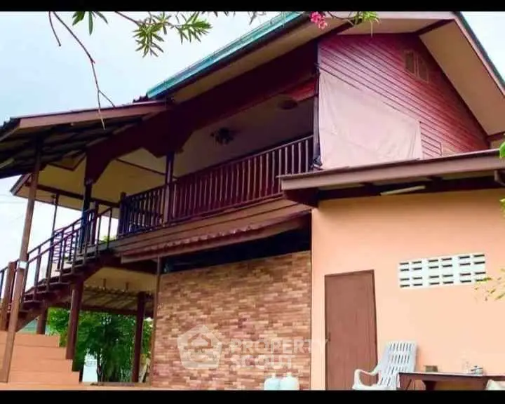 Charming two-story house with spacious balcony and rustic brick facade, perfect for serene living.