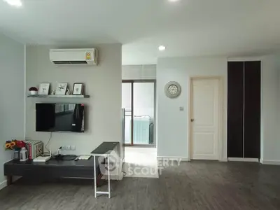 Modern living room with sleek design, featuring air conditioning and wall-mounted TV, leading to a balcony.