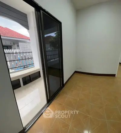 Bright room with sliding glass door leading to a small balcony, showcasing modern tile flooring.