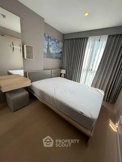 Modern bedroom with stylish decor and large window offering natural light.