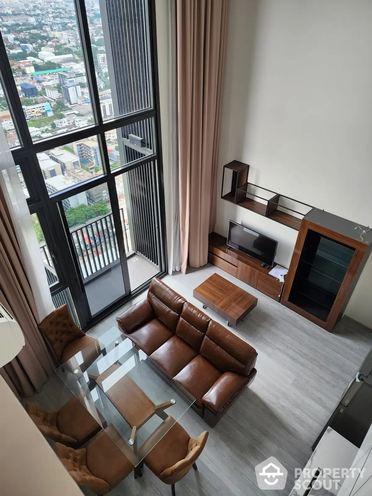 Spacious high-rise living room with floor-to-ceiling windows offering an expansive city view, modern furniture, and elegant interior design.