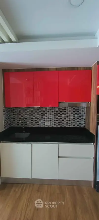 Modern kitchen with red cabinets and sleek black countertop