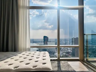 Luxurious bedroom with stunning cityscape view through large windows, featuring a cozy bed and elegant decor.