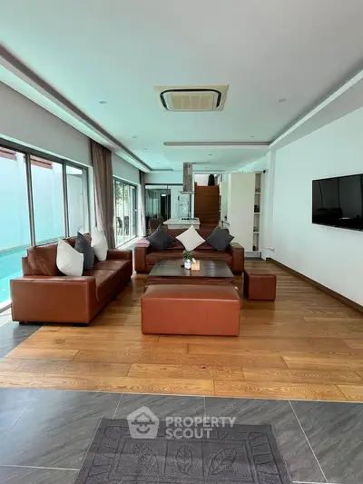 Luxurious living room with leather sofas and pool view, perfect for modern living.