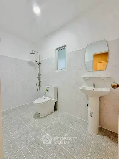 Modern bathroom with sleek fixtures and minimalist design, featuring a shower and toilet.