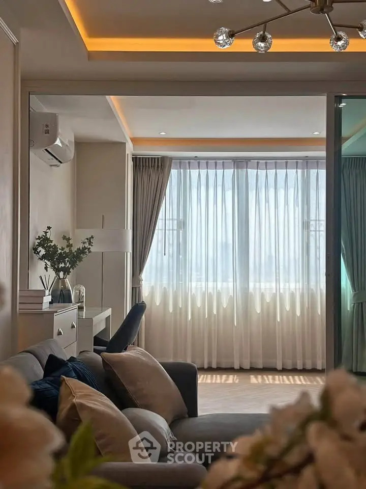 Elegant living room with modern lighting and large window, featuring cozy seating and stylish decor.