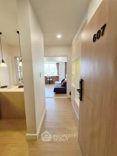 Modern apartment entrance with view into stylish living room and kitchen area, showcasing open layout and cozy design.