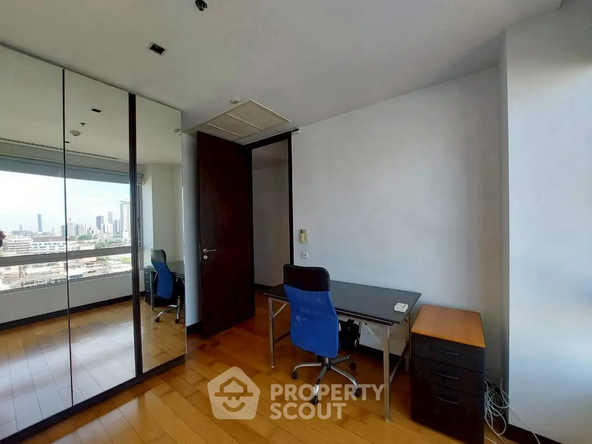 Modern study room with city view, mirrored closet, and sleek desk setup.