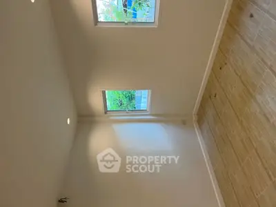 Bright empty room with two windows and wooden flooring, perfect for customization.