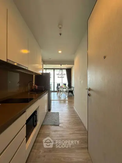 Modern kitchen with sleek cabinetry leading to a bright dining area with large windows.