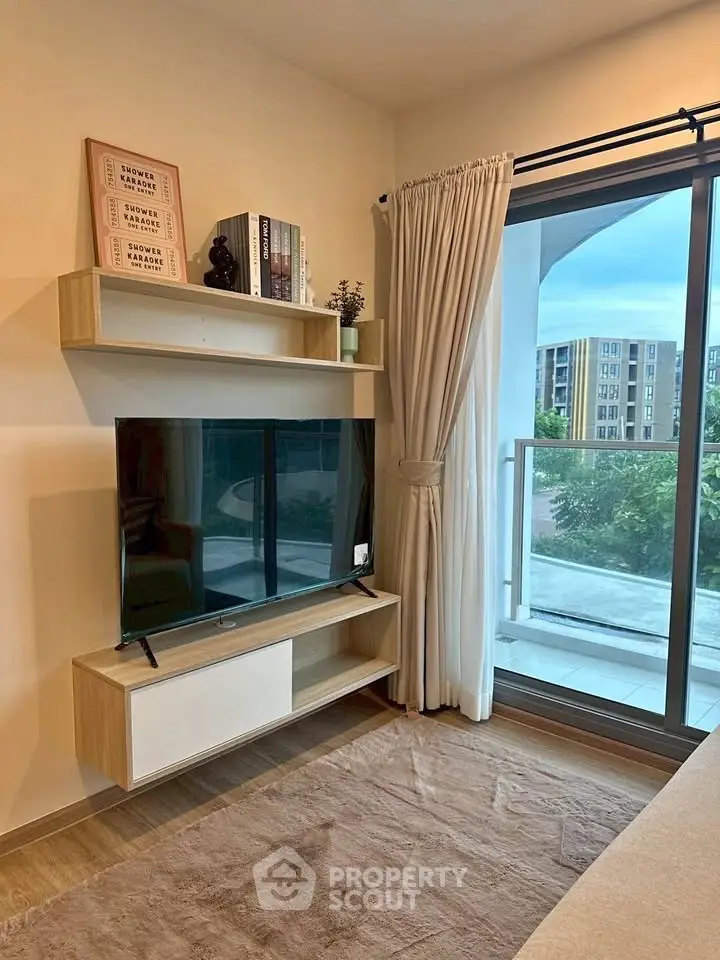 Modern living room with sleek TV setup and balcony view in stylish apartment.