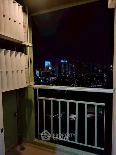 Night view from a high-rise balcony overlooking city skyline with modern buildings.