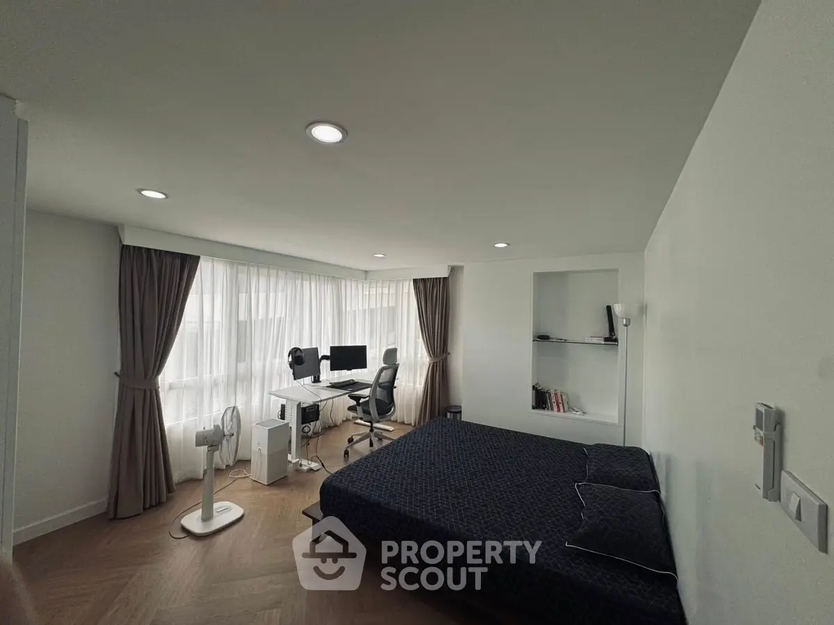 Modern bedroom with study area and large windows for natural light.