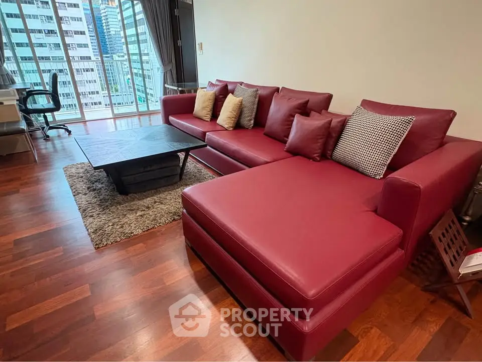 Spacious living room with red leather sofa and city view, perfect for modern urban living.