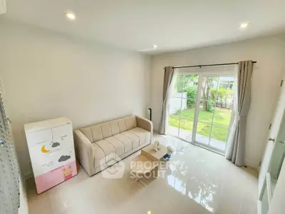 Bright living room with cozy sofa and garden view through sliding glass doors.