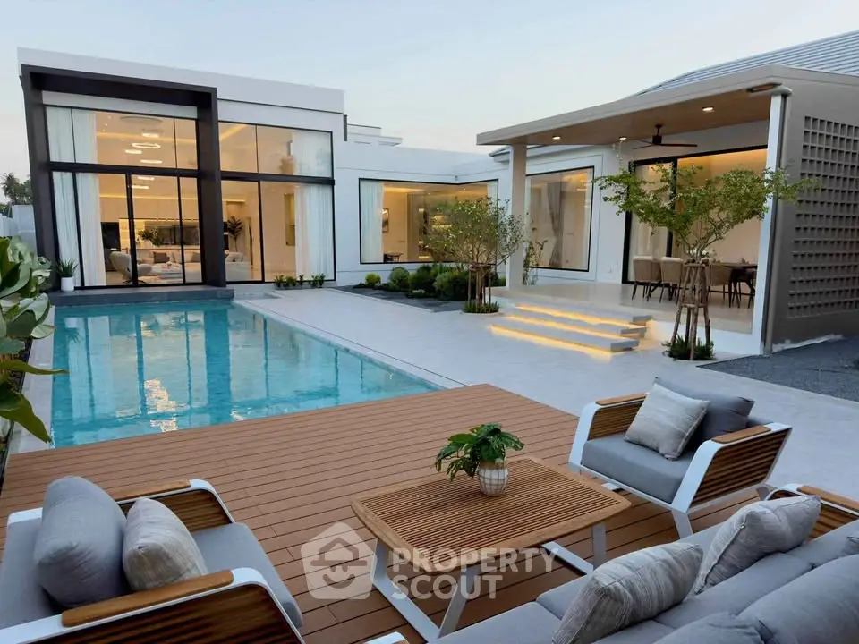 Luxurious modern home with stunning pool and elegant outdoor seating area, perfect for relaxation and entertainment.
