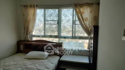 Cozy bedroom with large window and natural light, featuring a single bed and elegant curtains.