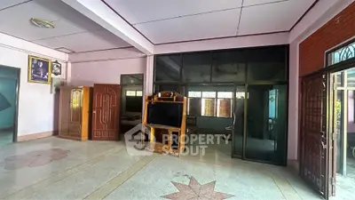 Spacious living room with large windows and traditional decor, featuring a TV stand and wooden furniture.
