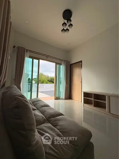 Spacious living room with large sliding doors leading to a balcony, offering a serene outdoor view.
