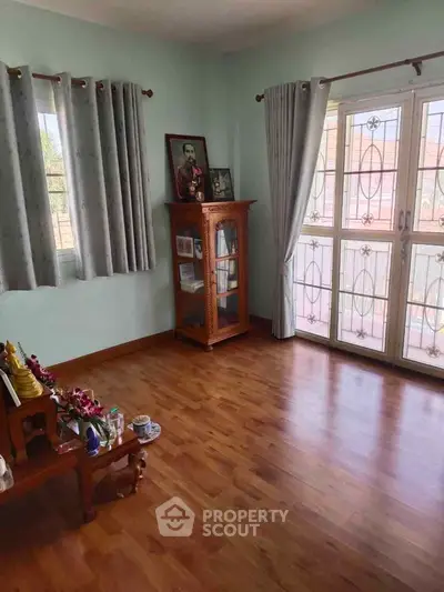 Spacious living room with wooden flooring and large windows for natural light.