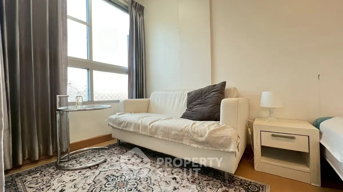 Cozy living room with modern white sofa, stylish rug, and natural light from large window.