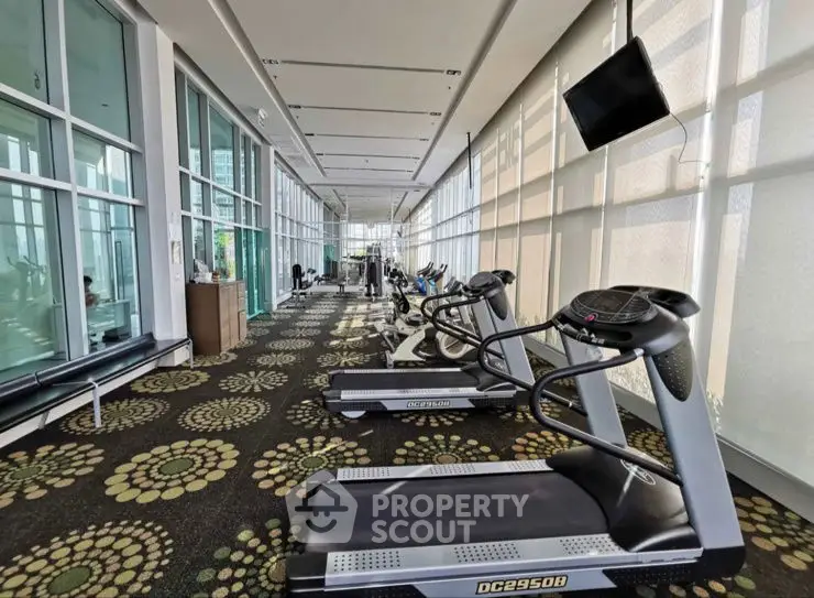 Spacious modern gym with treadmills and large windows in luxury residential building.
