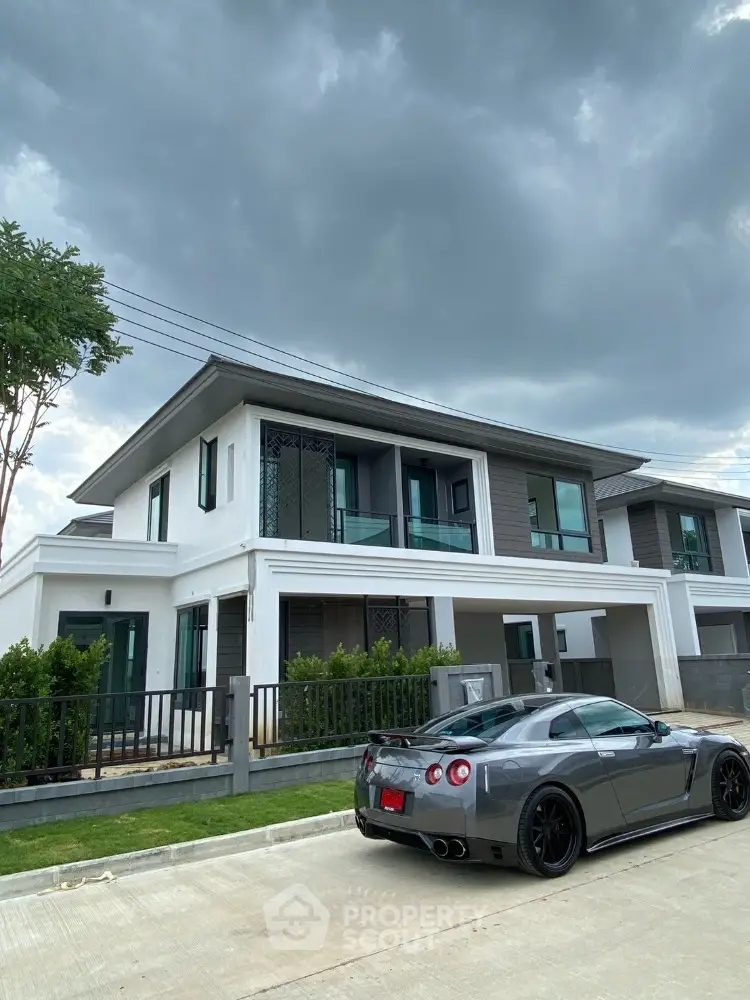 Modern two-story house with sleek design and luxury car parked in driveway under cloudy sky.