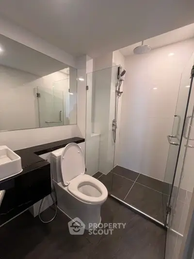 Modern bathroom with sleek design, featuring a glass shower enclosure and contemporary fixtures.