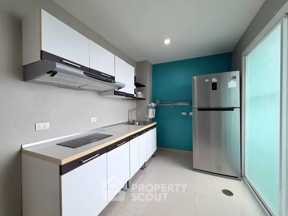 Modern kitchen with sleek cabinets and stainless steel fridge in a bright, spacious layout.