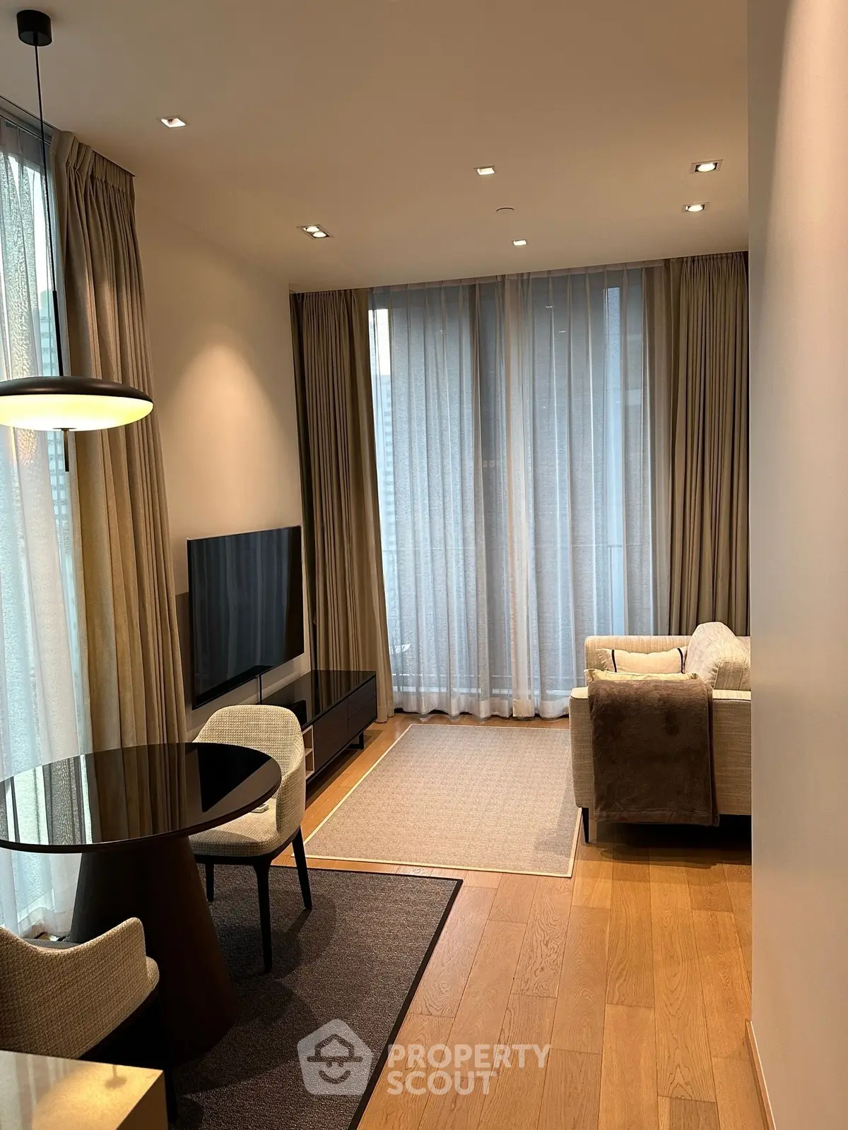 Modern living room with elegant decor, featuring a cozy seating area, stylish dining table, and floor-to-ceiling windows.