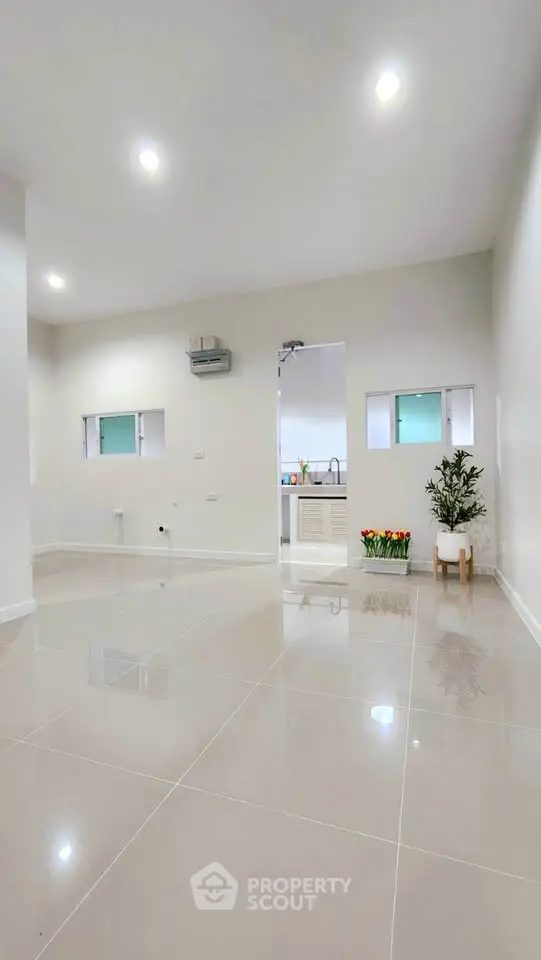 Spacious modern living room with glossy tiled floors and minimalistic decor.