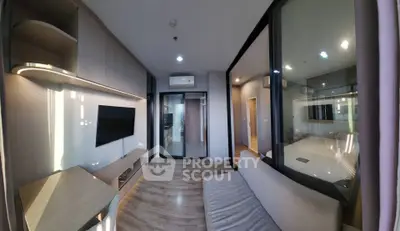 Modern living room with sleek design and glass partition, featuring a wall-mounted TV and cozy seating area.