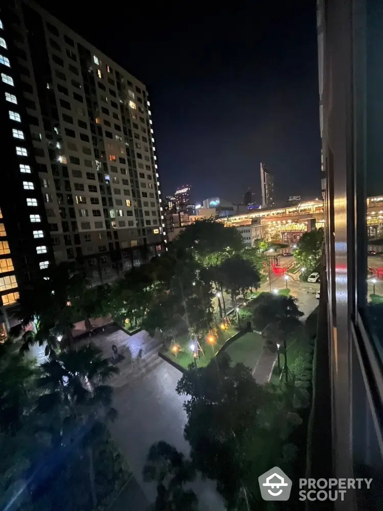 Stunning night view from high-rise apartment overlooking cityscape and illuminated garden.