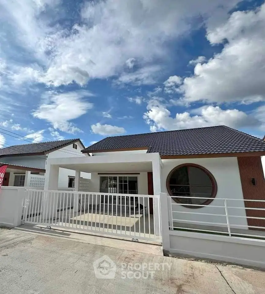 Charming modern house with unique circular window and sleek white facade under a vibrant blue sky.