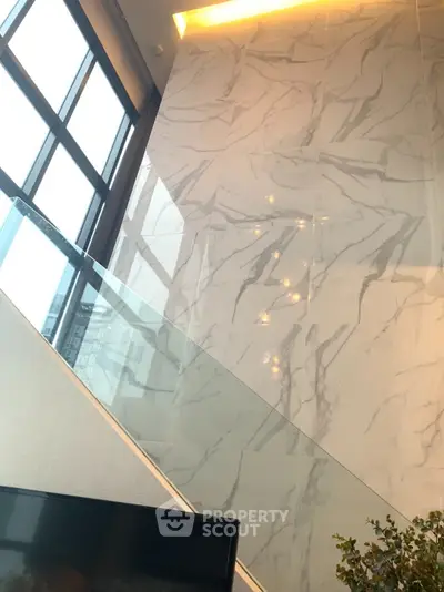 Luxurious modern interior with marble wall and large windows in high-rise apartment.