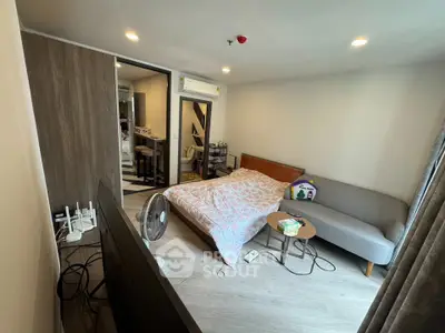 Cozy bedroom with modern decor and natural light, featuring a comfortable bed and stylish sofa.