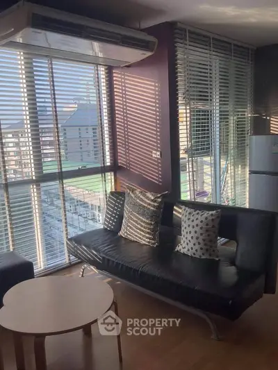 Modern living room with large windows and stylish furniture in a high-rise apartment.