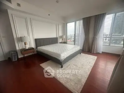 Spacious bedroom with city view, hardwood floors, and elegant decor in modern apartment.