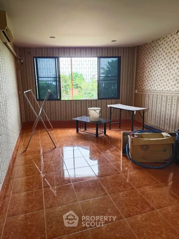 Spacious room with tiled floor and large window, ideal for versatile use.
