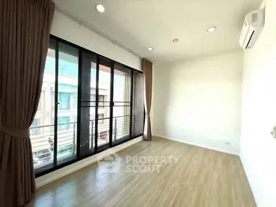 Spacious empty room with large windows and wooden flooring, perfect for customization.