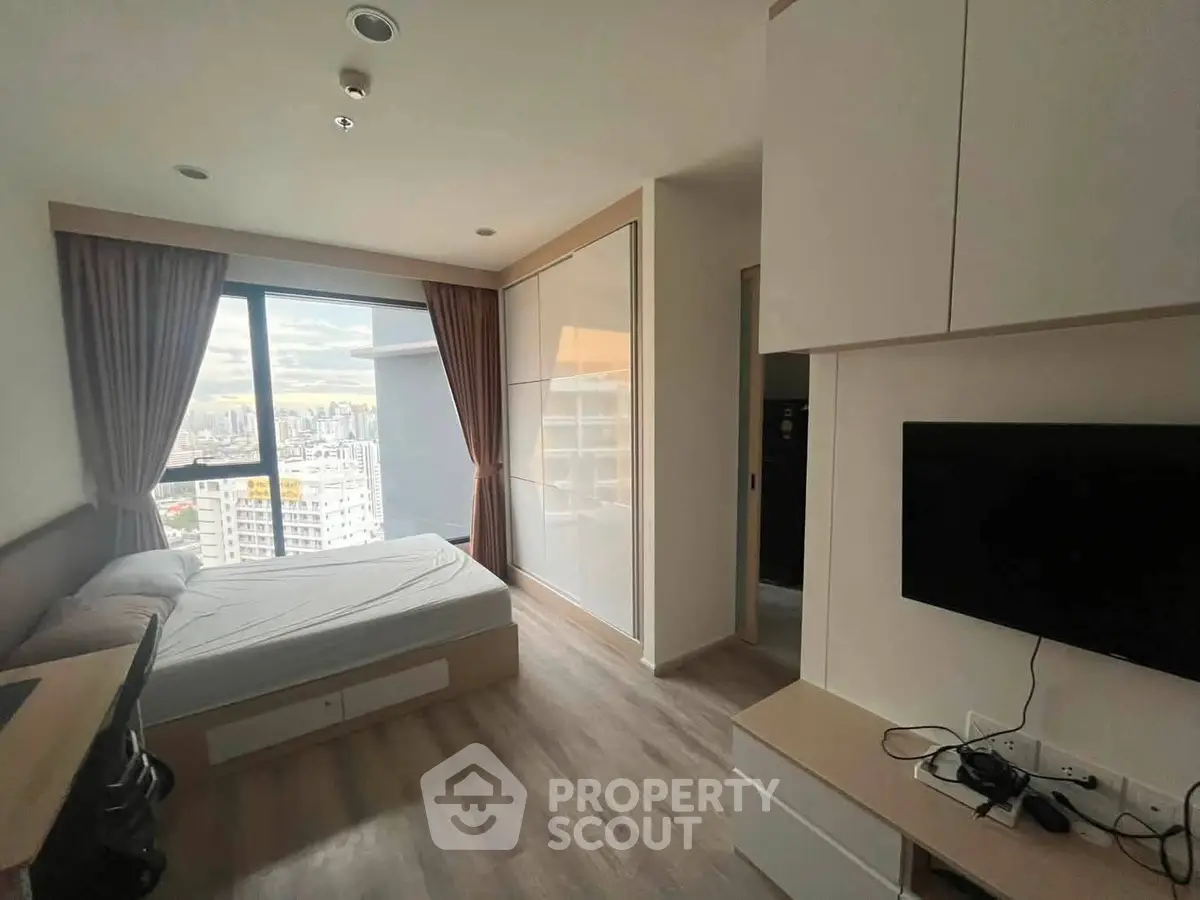 Modern bedroom with city view, featuring sleek furniture and ample natural light.