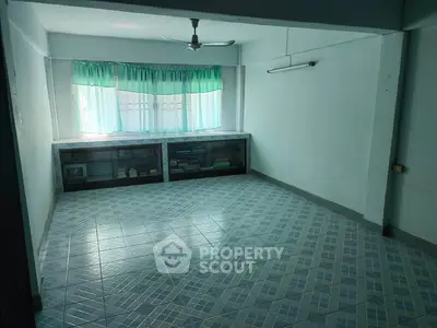 Spacious room with tiled floor and large window, ideal for versatile use.