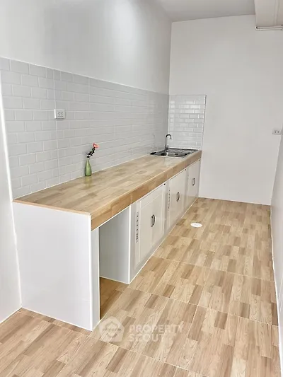 Modern minimalist kitchen with wooden countertops and white tile backsplash