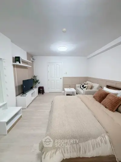 Spacious modern bedroom with cozy decor and neutral tones, featuring a comfortable bed and stylish furnishings.