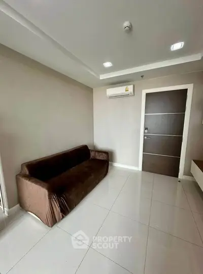 Modern living room with sleek brown sofa and air conditioning, featuring minimalist design and glossy tiled flooring.