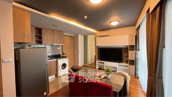 Modern open-plan living room with kitchen, featuring sleek appliances and stylish decor.