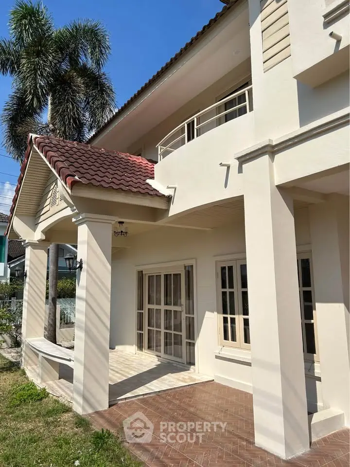 Elegant two-story home with red-tiled roof and spacious balcony, perfect for family living.