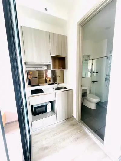 Modern compact kitchen with sleek cabinetry and adjacent bathroom in a stylish apartment.