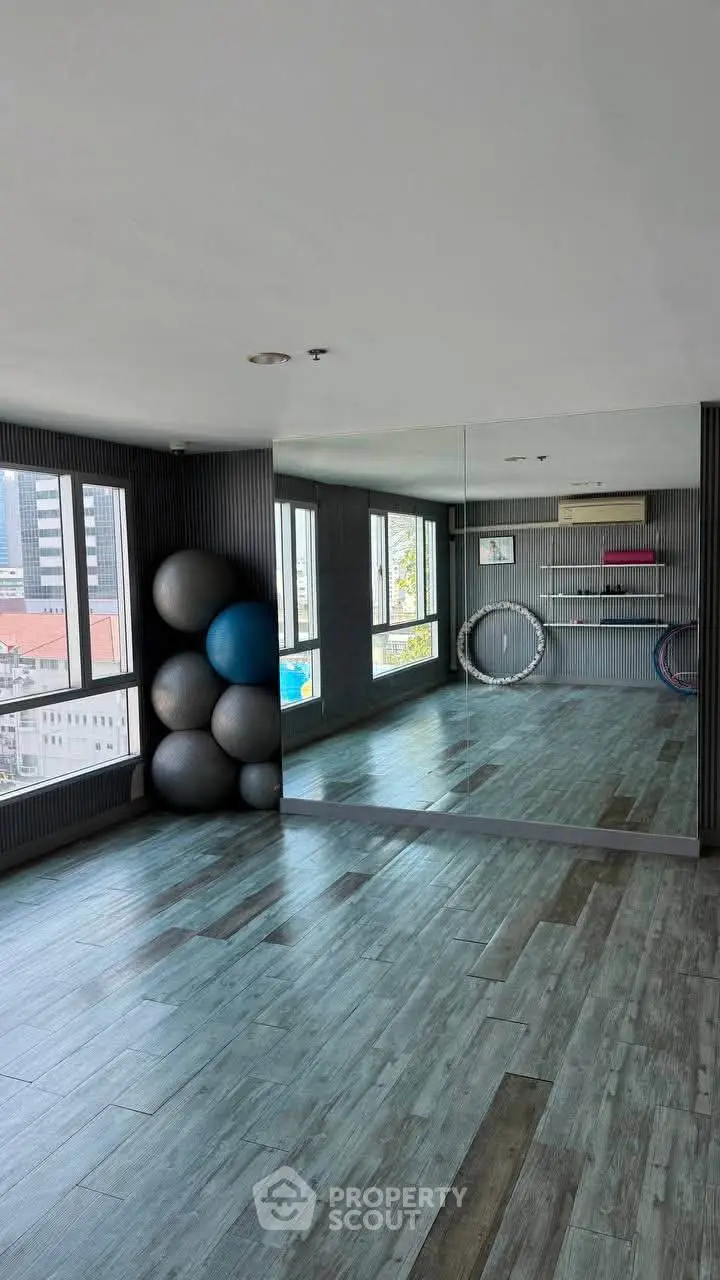 Spacious gym with mirrored wall and city view, perfect for fitness enthusiasts.
